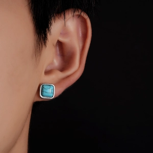Detailed view of vintage turquoise stud earring with silver metal frame on model