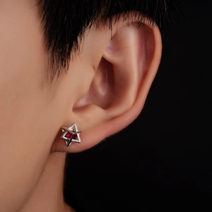 Close-up of silver hexagram stud earring with a bright red zircon inlay on person