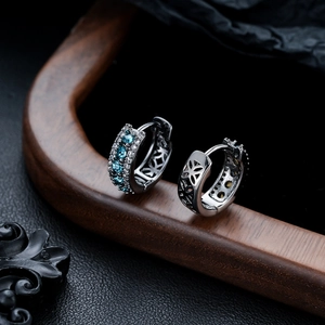Vue macro de boucles d'oreilles créoles avec pierres bleues et filigrane floral