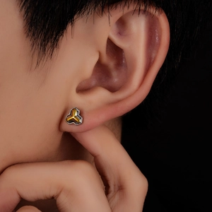 Macro view of a silver clover stud earring with yellow inlay worn on an earlobe