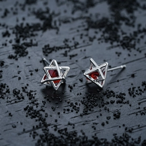 Macro view of silver star stud earrings featuring a faceted red zircon gemstone