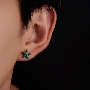 Close-up of a green starfish stud earring with silver metallic edges on a model's ear