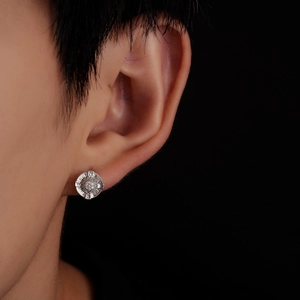 Macro view of round zircon compass earrings with N S E W engraved letters on the edge