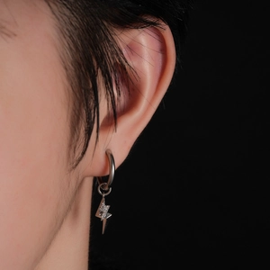 Close-up of a silver lightning bolt earring with inset diamonds on a real-life ear