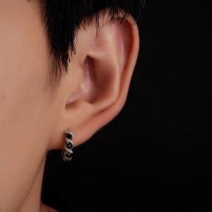 Macro shot of huggie hoop earring featuring black stones and white zircon pavé setting