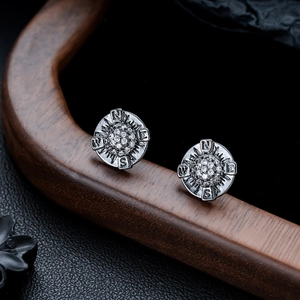 Detail of vintage silver compass earrings with pave-set zircon and engraved N-E-S-W directions