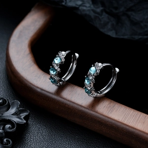 Detailed view of silver hoop earrings featuring blue zircon and white diamonds