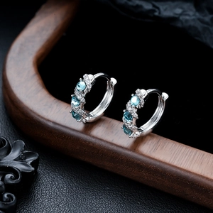 Detail view of silver hoop earrings with blue oval stones on a dark wooden stand