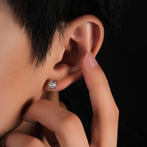 Silver snake-inspired stud earring with white and green gemstones on male model