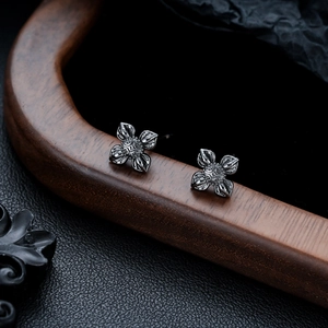 Gros plan détaillé de boucles d'oreilles lotus vintage sombres sur un présentoir texturé