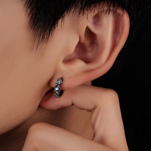 Close-up of black metal hoop earrings with three light blue zircon stones and white diamonds