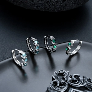 Luxe silver huggie earrings with emerald green and blue zircon pave set on dark stone