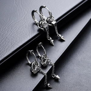 Detail of punk style titanium steel earrings featuring hexagonal nuts, chains and cone pendants