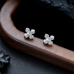 Gros plan de boucles d'oreilles lotus en argent avec détails ciselés sur support bois