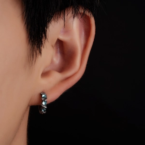 Macro shot of black huggie earring with three light blue stones and zircon inlay