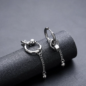 Detailed macro view of asymmetric punk style steel cone chain earrings on grey display