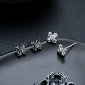 Set de quatre boucles d'oreilles lotus en argent avec gravures florales sur support noir