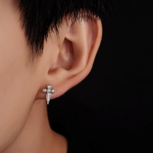 Macro detail of punk cross earring with zircon inlay on a model's ear