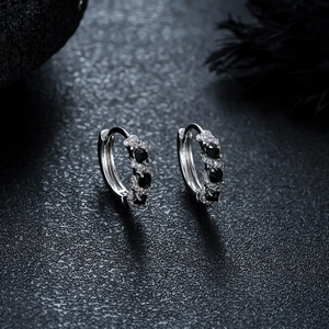 Detailed view of silver hoop earrings with alternating black and white zircon stones