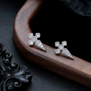 Macro shot of silver cross stud earrings with sparkling cubic zirconia on a wooden tray