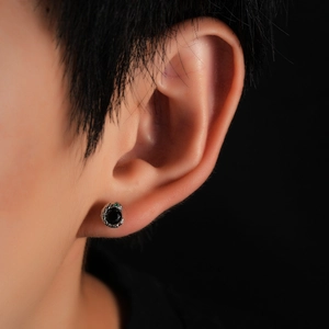 Macro shot of silver snake earring for men with black gemstone and green eye detail