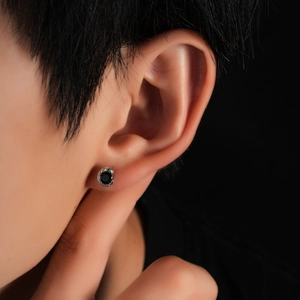 Detailed view of silver snake-scale stud earring with a polished black round gemstone