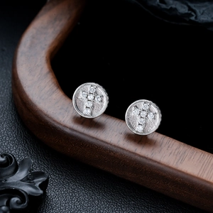 Gros plan de boucles d'oreilles argentées avec croix en zircon sur disque de métal texturé