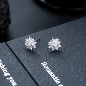 Detailed macro view of sparkling starburst stud earrings with zircon inlay in a gift box
