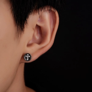 Gros plan du clou d'oreille croix noir avec oxydes de zirconium sur fond sombre