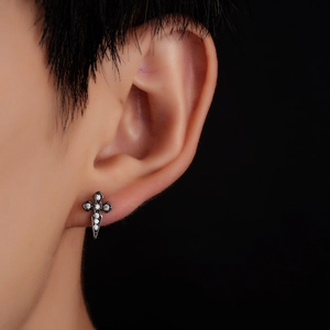 Close-up of punk gothic cross stud earring with white zircon inlay on model ear