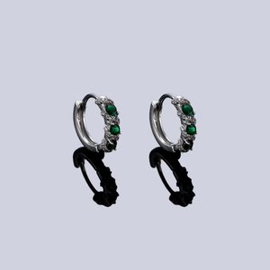 Silver hoop earrings with emerald green zircon stones and white diamond accents on black mirror