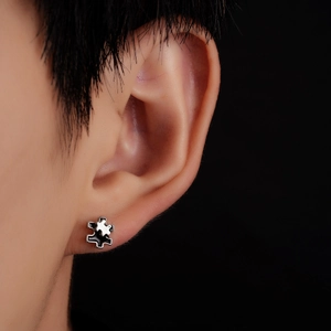 Macro shot of a puzzle-shaped earring with black and white enamel on a male model