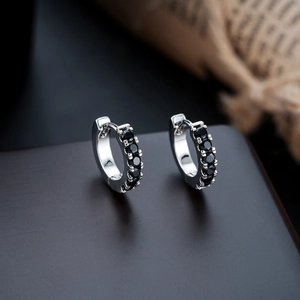 Macro detail of huggie earrings with five claw-set round black zircons on silver base