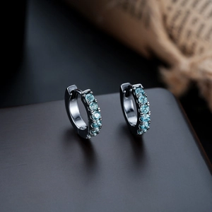Macro detail of black huggie hoop earrings with light blue zircons in a channel setting