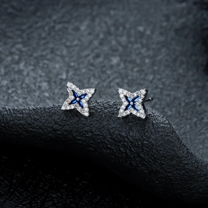 Close-up of star-shaped stud earrings with silver metal and blue cross inlay detail