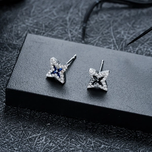 Macro view of four-pointed star stud earrings with micro-paved cubic zirconia and gems