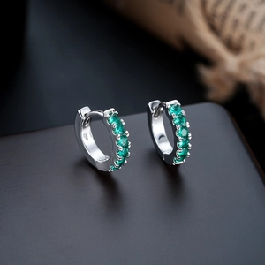 Close-up of S925 silver huggie earrings featuring pavé-set faceted green gemstones