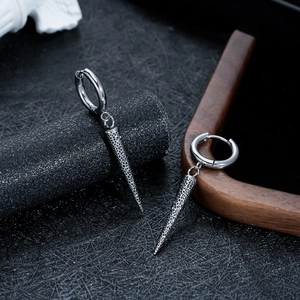 Dettaglio di orecchini punk in titanio argento con coni geometrici e trame incise