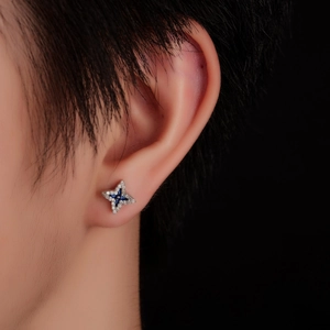 Macro shot of silver four-pointed star stud earring with blue gems and white zirconias