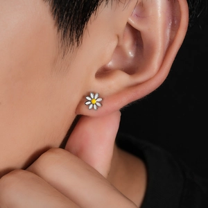 Daisy stainless steel stud earrings featuring white petals and yellow centers on ear