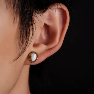 Macro side view of retro water drop stud earrings with marble stone and gold engraving