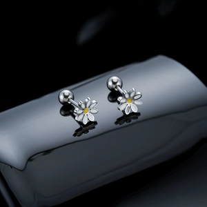 Macro shot of silver daisy earrings with white enamel petals and yellow center detail