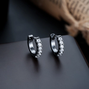 Detail of silver hoop earrings with a row of clear micro-pave crystals on dark background