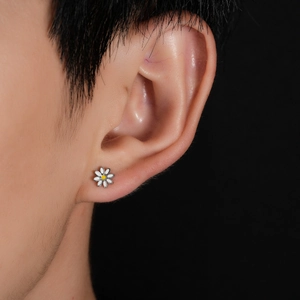Close-up of a small white daisy stud earring with a yellow center on a model's ear