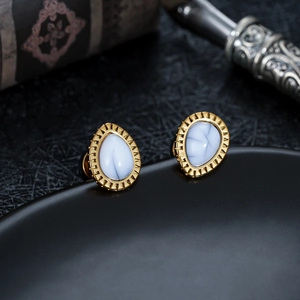 Macro shot of teardrop earrings with golden serrated edges and blue translucent stones