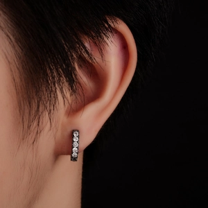 Macro view of black plated huggie earring with five sparkling cubic zirconia stones