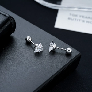 Macro shot of triangle-cut zircon stud earrings with screw-back on black leather surface