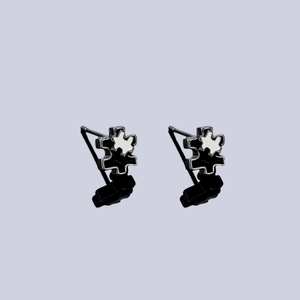 Irregular puzzle piece stud earrings in black and white enamel with silver edges