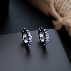 Detailed macro view of S925 sterling silver stamp on black huggie earrings with purple gems