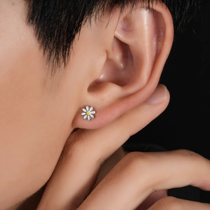 Daisy shaped stainless steel stud earring with white enamel petals on a female model